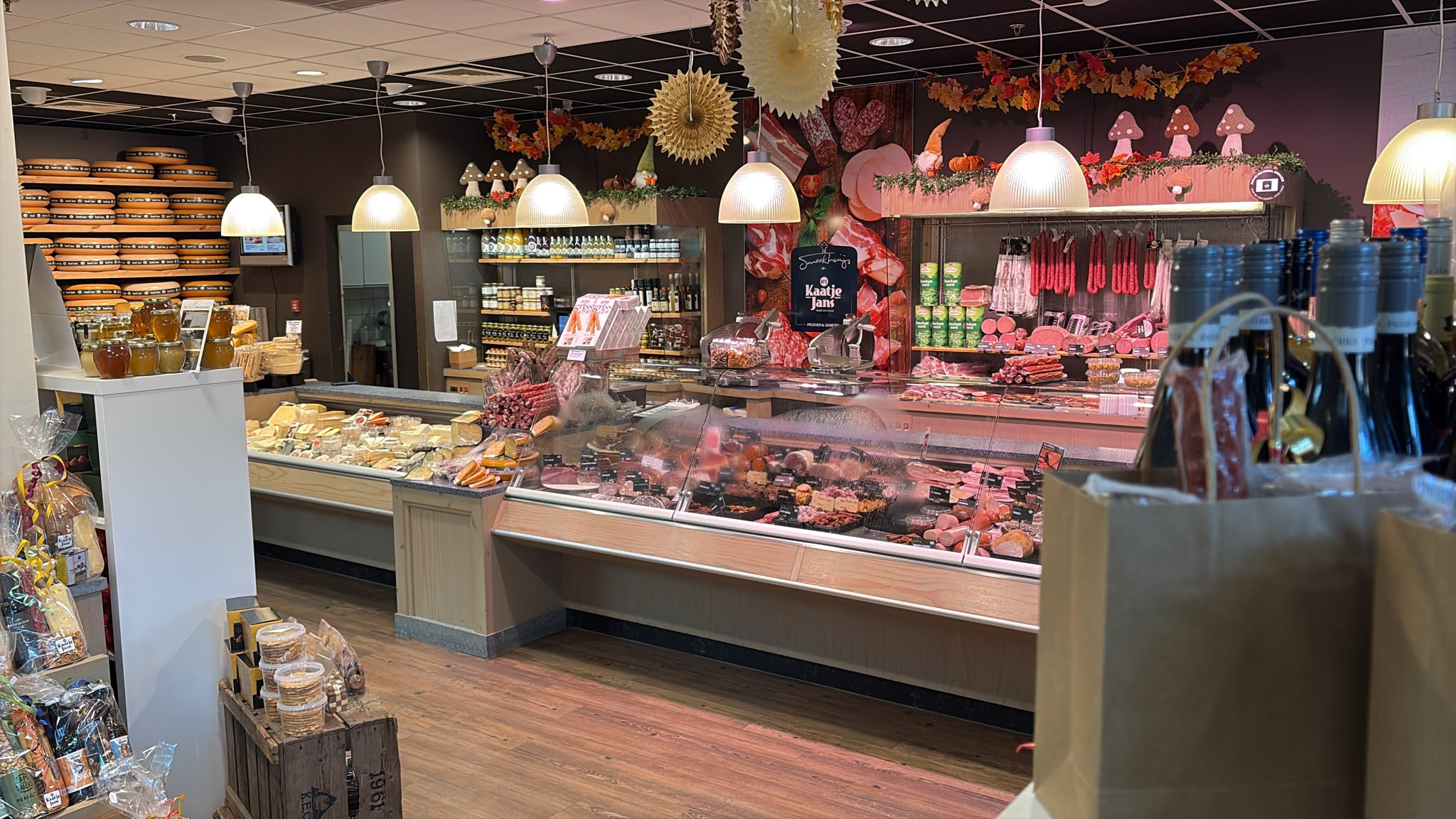 Lange glazen toonbank gevuld met vleeswaren en tapas in een winkel met houten vloer en het logo van Kaatje Jans op de wand.