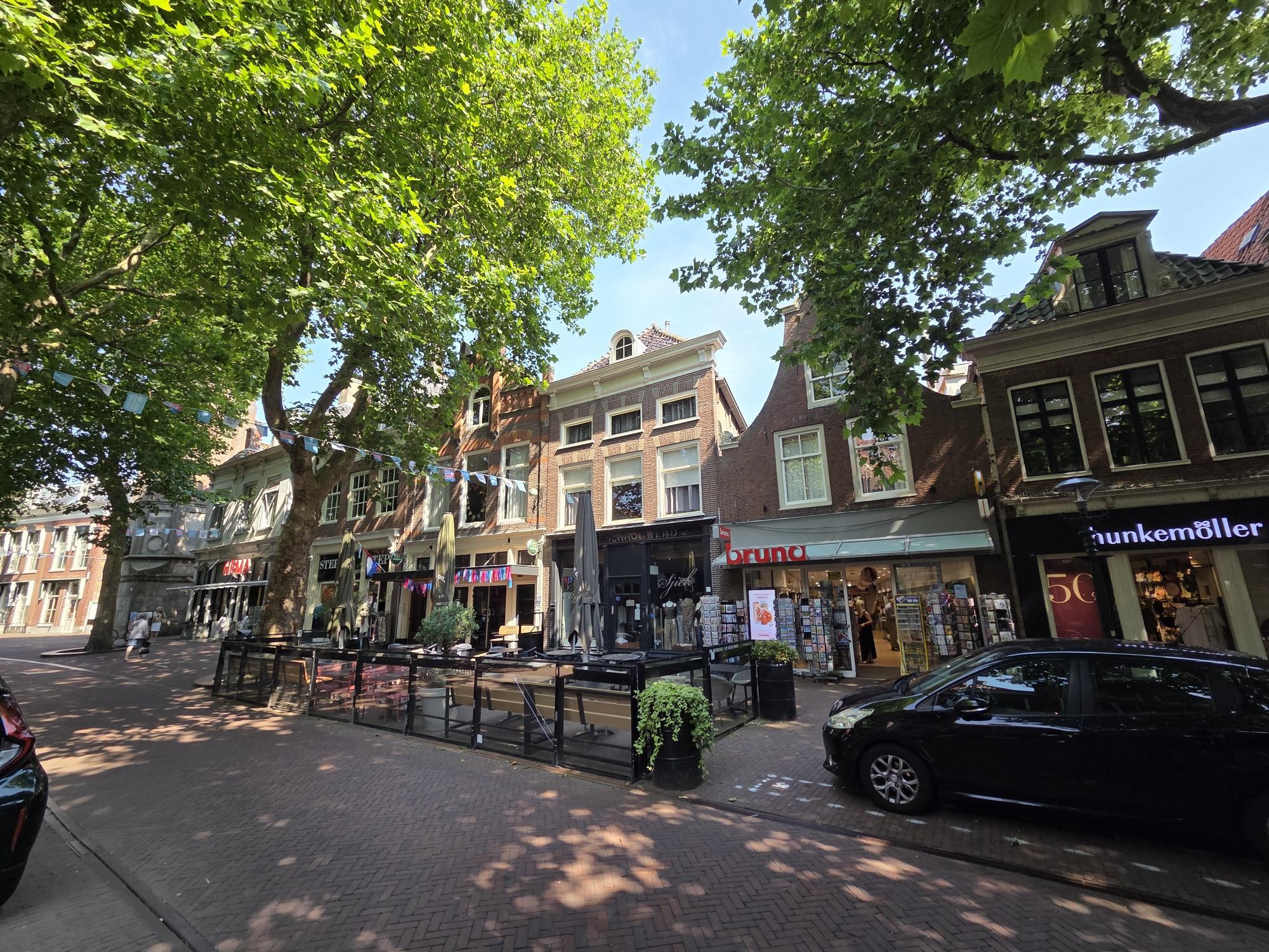 Een winkelstraat met bomen en historische gevels waarin onder meer Bruna en Hunkemöller zijn gevestigd.