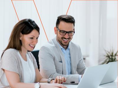 Twee mensen werken samen lachend achter laptops in een kantooromgeving, met het Valenta-logo zichtbaar.