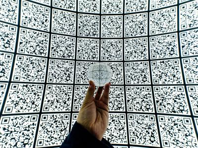 Hand houdt een glazen bol vast tegen een achtergrond van QR-codes, wat privacy-implicaties symboliseert.