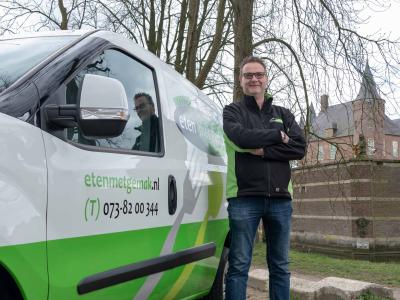 Man poseert naast busje van Eten met gemak met kasteel op de achtergrond.