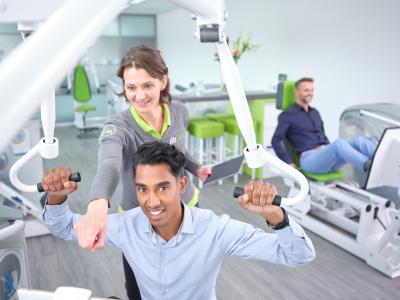 Een instructeur begeleidt een man bij fit20-krachttraining in een moderne fitnessstudio.