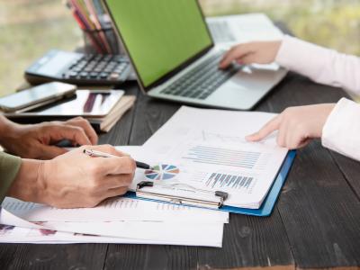 Twee mensen analyseren sport- en fitnessgegevens met grafieken en een laptop.