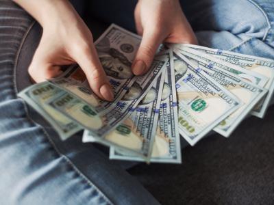 Personenhanden die Amerikaanse honderd-dollarbiljetten vasthouden.