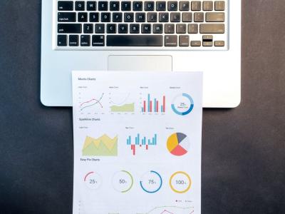 Papier met kleurrijke grafieken ligt op een laptoptoetsenbord, symboliserend data-analyse en online vindbaarheid.