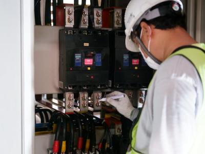 Technicus in veiligheidshesje voert controle uit op elektrische schakelkast.