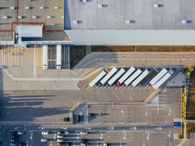 Luchtfoto van een distributiecentrum met geparkeerde vrachtwagens en auto's op een parkeerplaats.