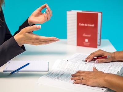 Twee personen bespreken documenten aan een tafel met een werkboek en notitieblok.