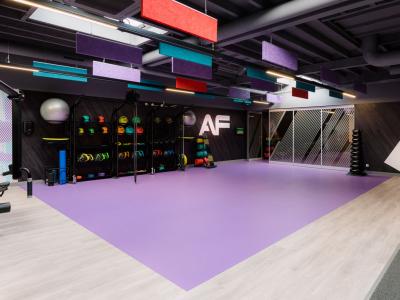 Moderne sportschool met paars vloeroppervlak, wandrekken vol kleurrijke fitnessaccessoires en grote spiegels.