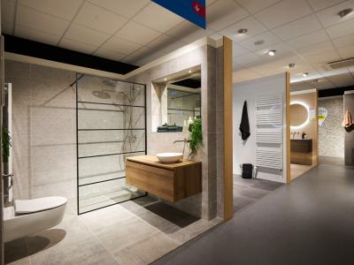 Moderne badkameropstelling bij Sanidirect met glazen douchewand, wastafelmeubel en verwarmingsradiator.