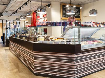 Interieur van een Leonidas-winkel met chocoladevitrine, geschenkverpakkingen en stijlvolle verlichting.