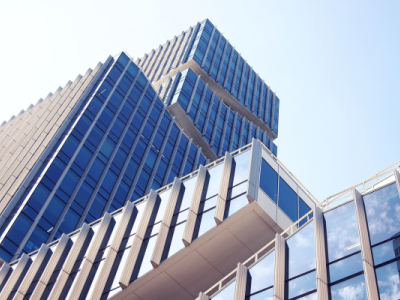 Modern kantoorgebouw met glazen gevels tegen een heldere hemel.