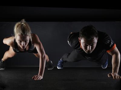 Twee personen doen push-ups in een fitnessruimte, gericht op krachttraining en uithoudingsvermogen.