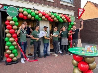 Teamleden van New York Pizza Sint Willebrord poseren bij de feestelijke opening onder een kleurrijke ballonboog.