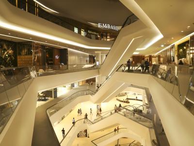 Moderne winkelgalerij met meerdere etages en roltrappen, verlicht met zachte verlichting.