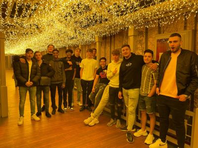 Groep jonge mannen poseert onder een verlichte hemel van kerstlichtjes in een warme, sfeervolle ruimte.