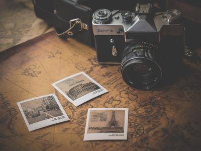 Analoge camera met zwart-wit vakantiefoto's en een ouderwetse kaart op de achtergrond.