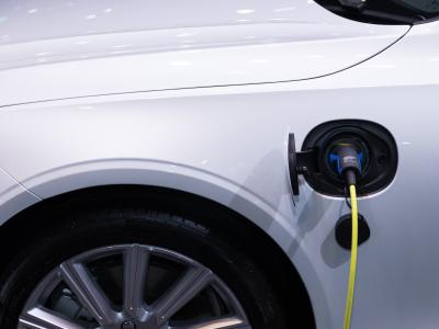 Elektrische auto met gele oplaadkabel aangesloten op de laadpoort aan de zijkant.