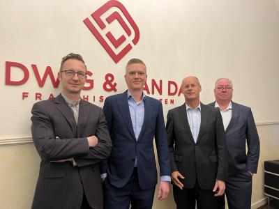 Vier mannen in zakelijke pakken voor het logo van DWG & Van Dijk Franchise Advocaten.