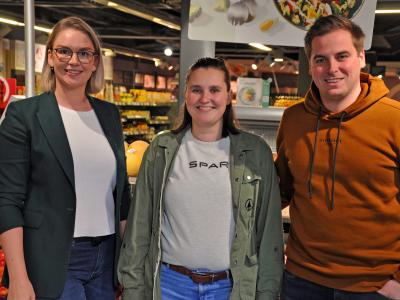 Drie mensen staan in een SPAR-winkel voor een fruitschap.
