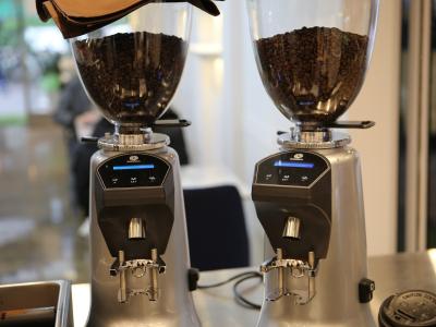 Twee elektrische koffiemolens met bonen op een toonbank in een zakelijke omgeving.