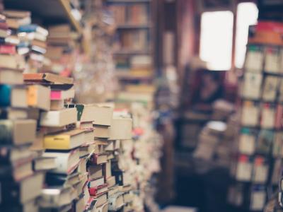 Een stapel boeken in een volle boekwinkel.