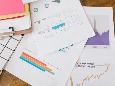 Verschillende geprinte grafieken en diagrammen verspreid over een houten tafel.