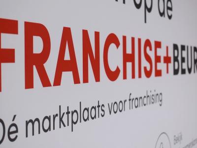 Banner met groot de tekst FRANCHISE+ BEURS en Dé marktplaats voor franchising op een witte achtergrond.