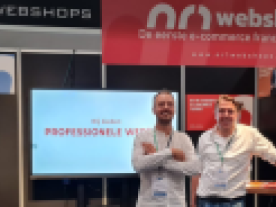 Drie mannen poseren bij een beursstand van NR1 Webshops met promotiemateriaal voor franchise webshops.
