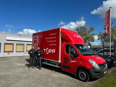 Twee mannen voor een rood Topp-bedrijfsvoertuig voor een pand met de tekst Wij maken hygiëne makkelijk.