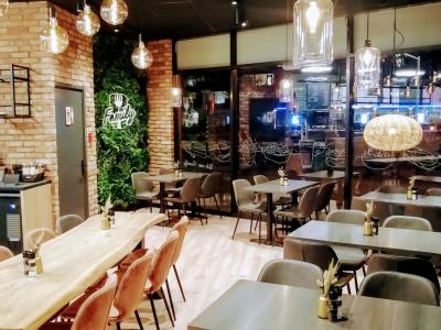 Interieur van een stijlvol restaurant met houten tafels, moderne stoelen en sfeervolle verlichting.