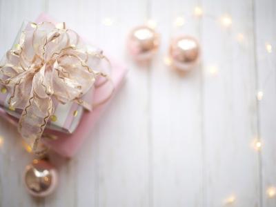 Ingepakt cadeau met sierlijke strik, omgeven door sfeerverlichting op een witte ondergrond.