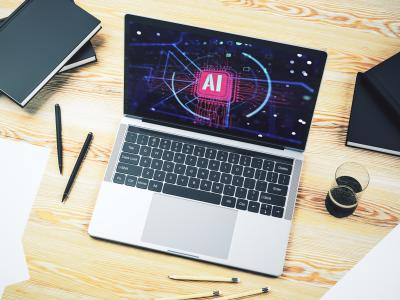 Laptop met AI-beeldscherm op bureau met notitieblokken, pennen, potloden en glas.