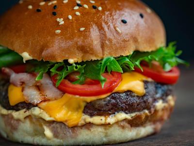 Sappige hamburgersandwich met sla, tomaat, spek en kaas op een sesambroodje.
