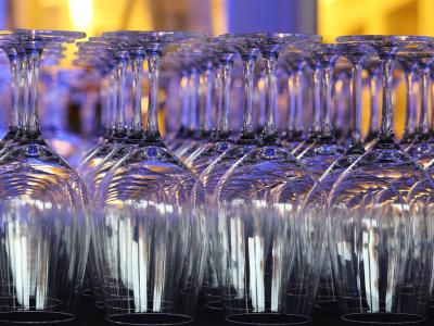 Rijen omgekeerde wijnglazen geëtaleerd in sfeervol blauw licht, perfect voor een feestelijke gelegenheid.