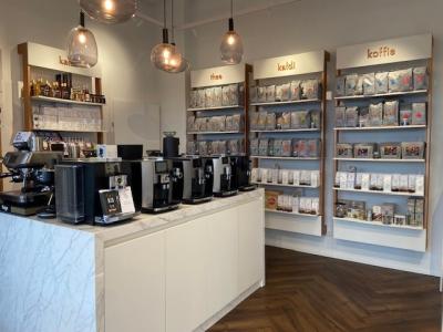 Moderne Kaldi-winkelinterieur met espressomachines en schappen vol koffie- en theeproducten.