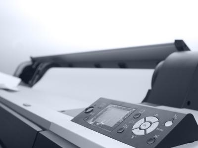 Grote labelprinter met bedieningspaneel en papierinvoer in een moderne kantooromgeving.