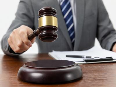 Rechter slaat met hamer op tafel naast documenten en pen, symboliserend juridische uitspraak.