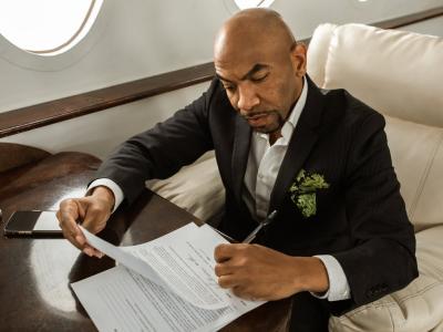 Man in pak ondertekent documenten aan tafel in een luxe interieur.
