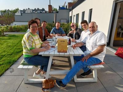 Zakelijke bijeenkomst buiten op een terras in Edegem met zeven mensen rond een witte picknicktafel.