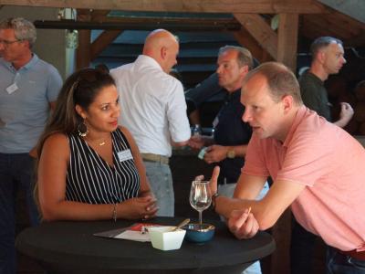 Deelnemers praten en netwerken rond statafels tijdens de Franchise+ barbecue 2024.