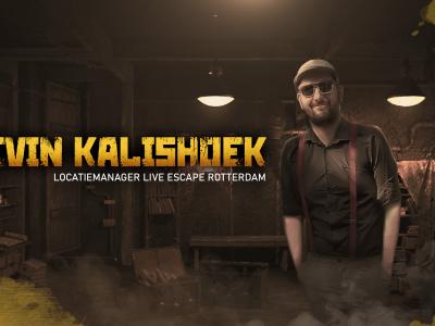 Man met hoed en zonnebril in een sfeervolle escape room, met op de achtergrond houten meubels en subtiele belichting.