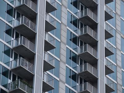 Hoog appartementencomplex met glazen gevels en balkons aan de buitenkant.