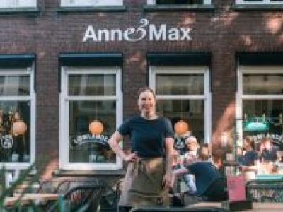 Verena Stevens staat voor de gevel van Anne&Max met klanten op het terras op de achtergrond.