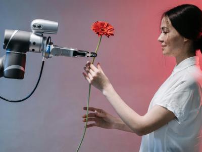 Een vrouw ontvangt een bloem van een robotarm in een futuristisch verlichte omgeving.