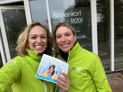 Twee lachende vrouwen in groene fit20-jassen bij een nieuw te openen fit20-locatie in Oud-Beijerland.