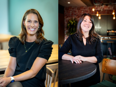 Twee glimlachende vrouwen zittend aan tafels in een moderne kantooromgeving.