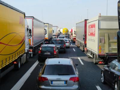 Drukke snelweg vol vrachtwagens met opvallende reclames tussen personenauto’s.