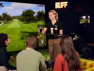 Groep mensen geniet van drankjes in een virtuele golfomgeving met RUFF-merk op de achtergrond.