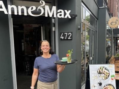 Vrouw met serveerblad voor ingang van Anne&Max Fahrenheit met huisnummer 472 zichtbaar.